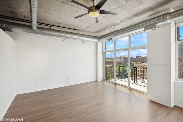 unfurnished room with wood-type flooring, ceiling fan, and a wall of windows