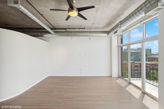 unfurnished room with expansive windows, hardwood / wood-style floors, and ceiling fan