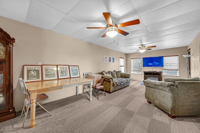 living room featuring a drop ceiling, ceiling fan, and light colored carpet