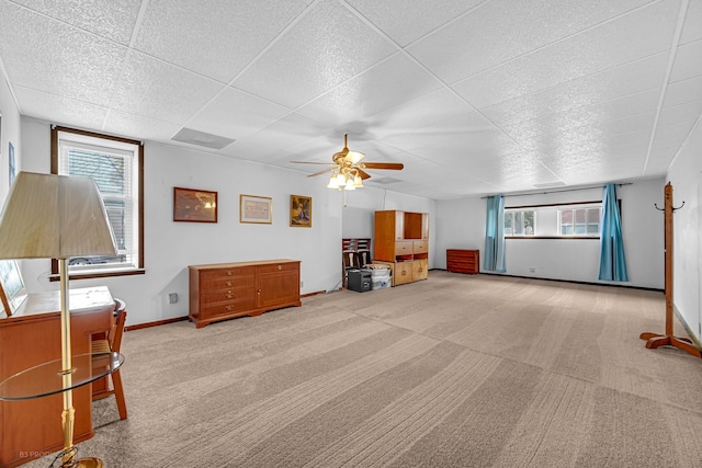 carpeted living room featuring a paneled ceiling, ceiling fan, and a healthy amount of sunlight