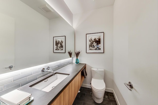 bathroom with tile flooring, tasteful backsplash, toilet, and vanity