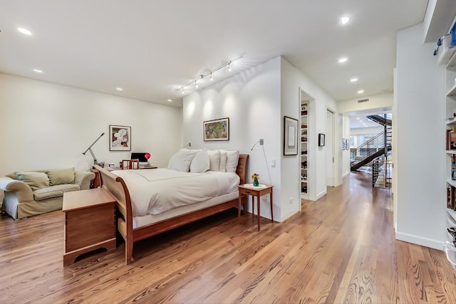 bedroom with hardwood / wood-style floors and rail lighting