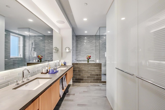 bathroom featuring backsplash, a shower with shower door, oversized vanity, and double sink