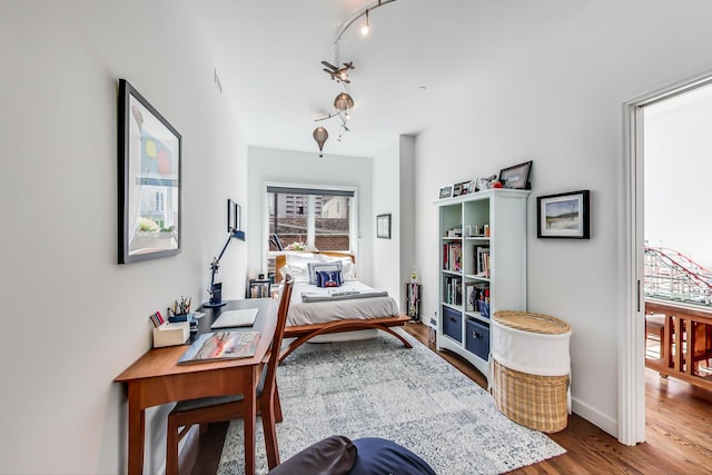 office area with wood-type flooring and track lighting