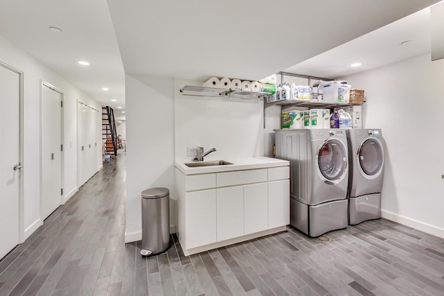 laundry room with washer and dryer, sink, and wood-type flooring