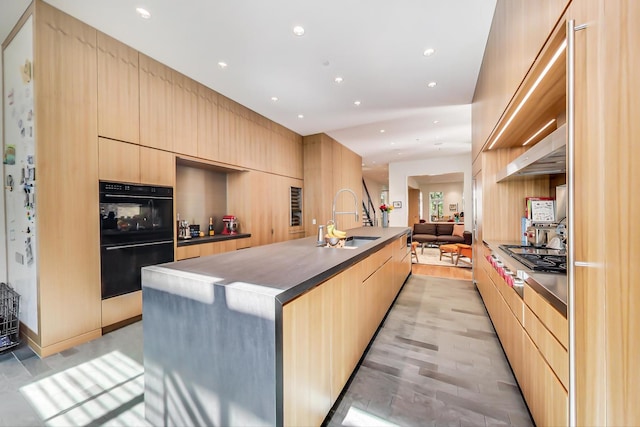 kitchen with sink, light hardwood / wood-style flooring, black double oven, and light brown cabinetry