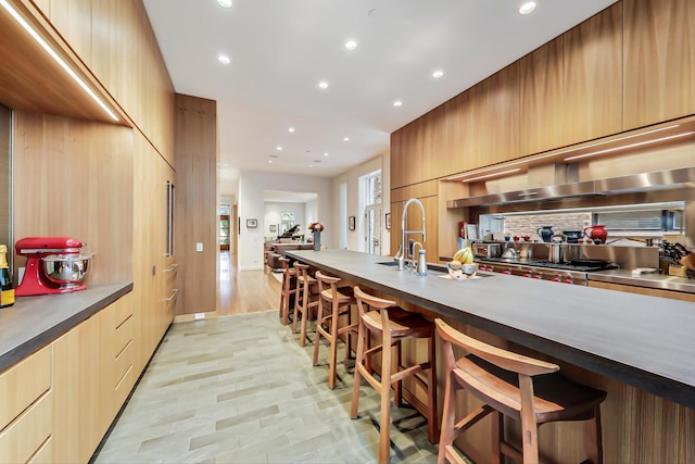 kitchen with a kitchen breakfast bar, sink, light tile flooring, and tasteful backsplash