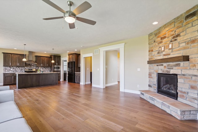 unfurnished living room featuring visible vents, baseboards, ceiling fan, light wood-type flooring, and a fireplace