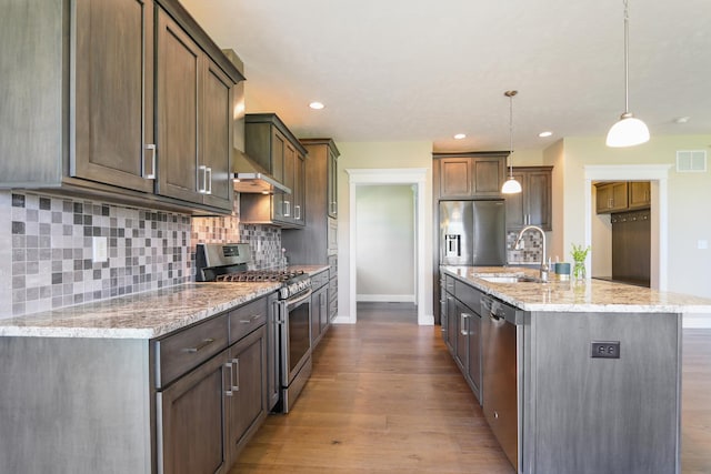 kitchen with visible vents, a sink, tasteful backsplash, wood finished floors, and stainless steel appliances