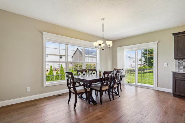 dining room with dark wood finished floors, baseboards, visible vents, and a chandelier