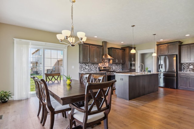 dining space with recessed lighting, an inviting chandelier, and wood finished floors