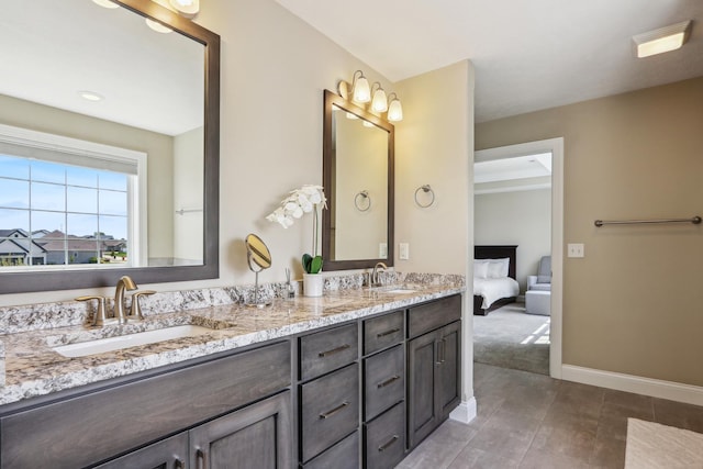 ensuite bathroom with a sink, baseboards, double vanity, and tile patterned floors