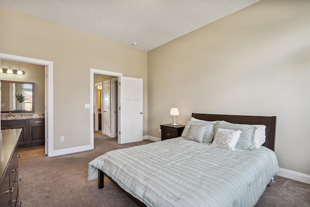 carpeted bedroom with ensuite bath and baseboards