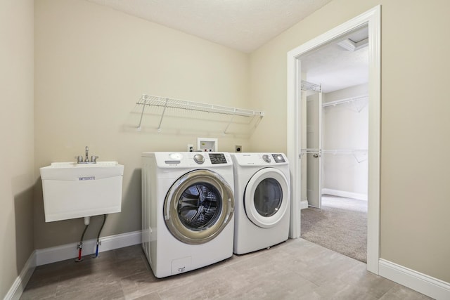 washroom with baseboards, laundry area, a sink, a textured ceiling, and washing machine and dryer