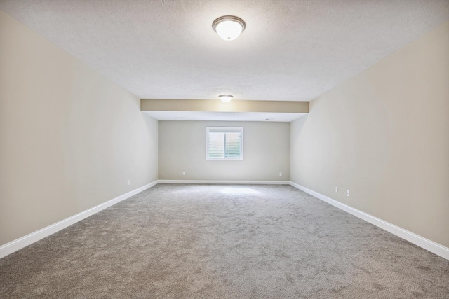 carpeted empty room with baseboards and a textured ceiling