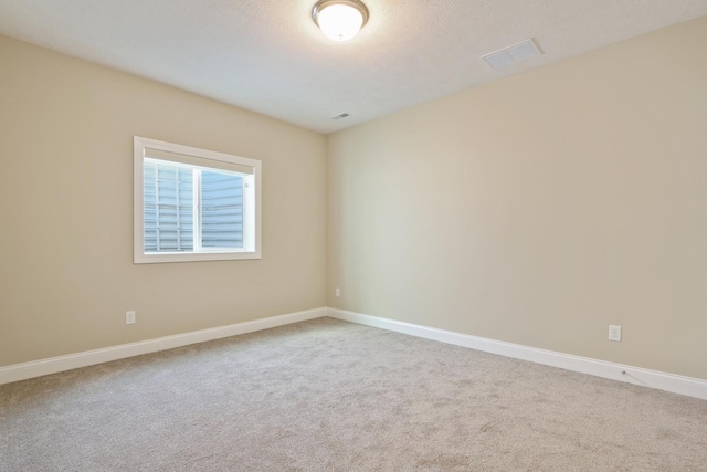 carpeted spare room featuring baseboards and visible vents