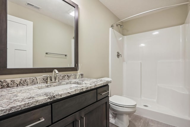 full bathroom featuring vanity, toilet, visible vents, and a stall shower