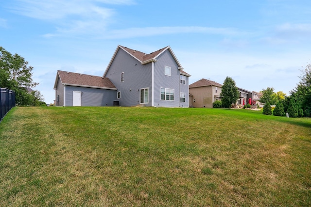 back of property with a lawn and fence