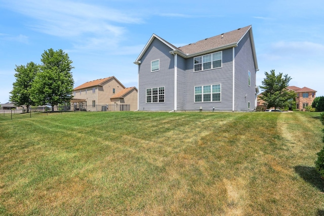 rear view of house featuring a yard and fence