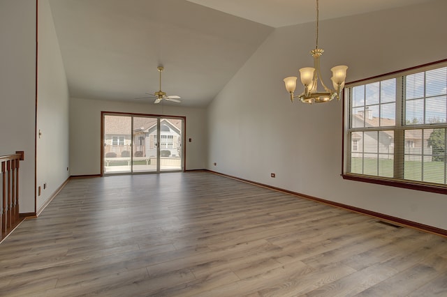 empty room with ceiling fan with notable chandelier, light wood-type flooring, and lofted ceiling