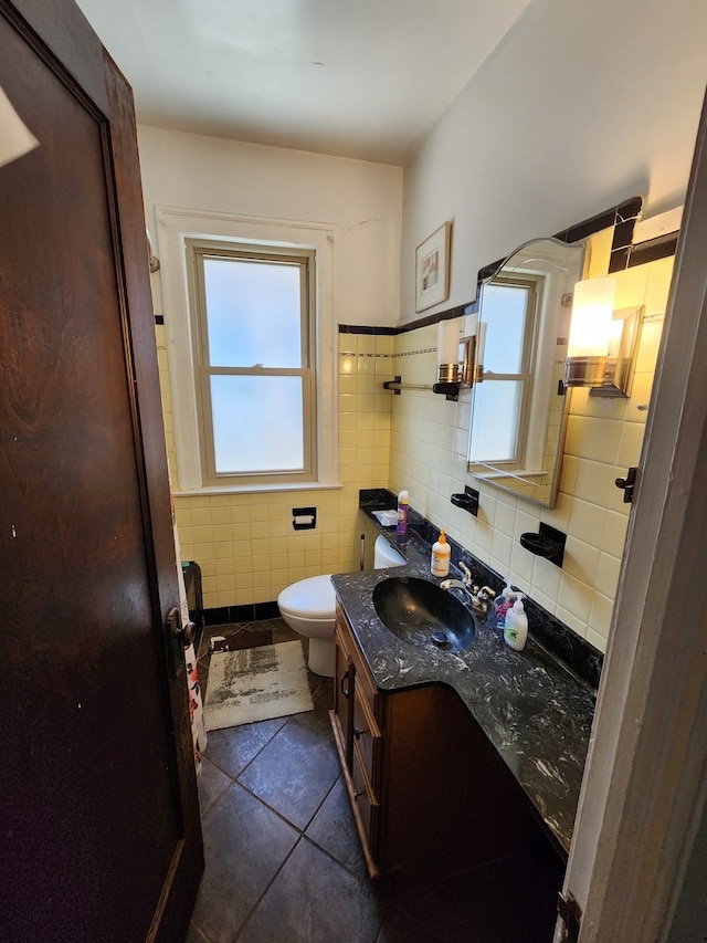 bathroom with tile patterned flooring, vanity, toilet, and tile walls