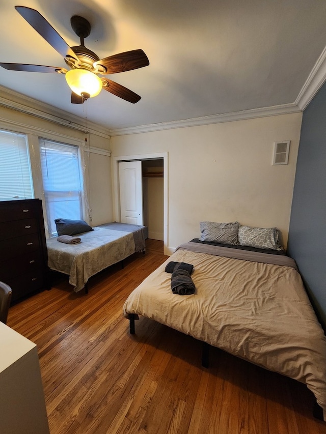 bedroom featuring ceiling fan, a closet, hardwood / wood-style flooring, and ornamental molding