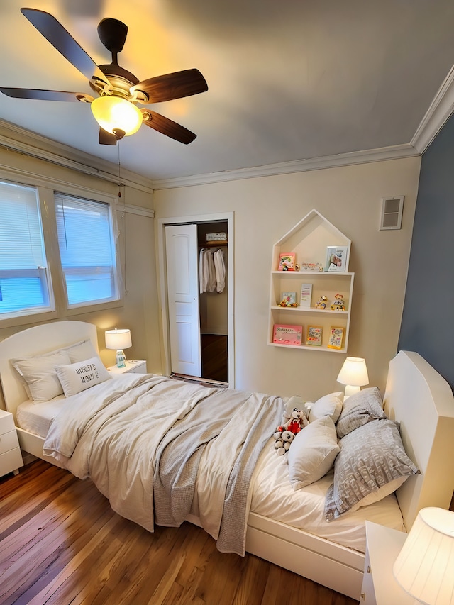 bedroom with a closet, ceiling fan, crown molding, and hardwood / wood-style flooring