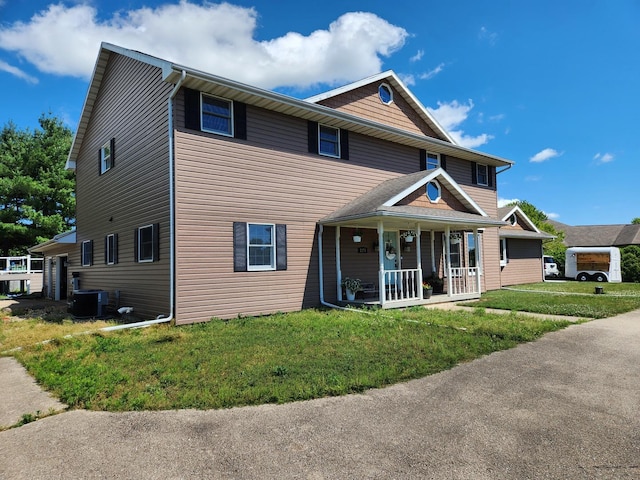 view of front of home with a porch, a front yard, and central AC