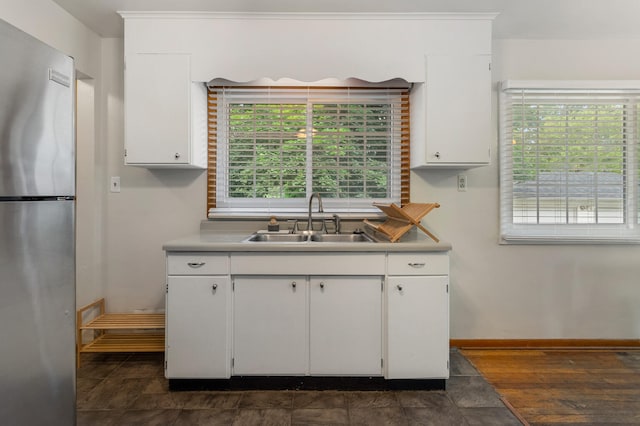 kitchen with stainless steel fridge, sink, white cabinets, and dark wood-type flooring