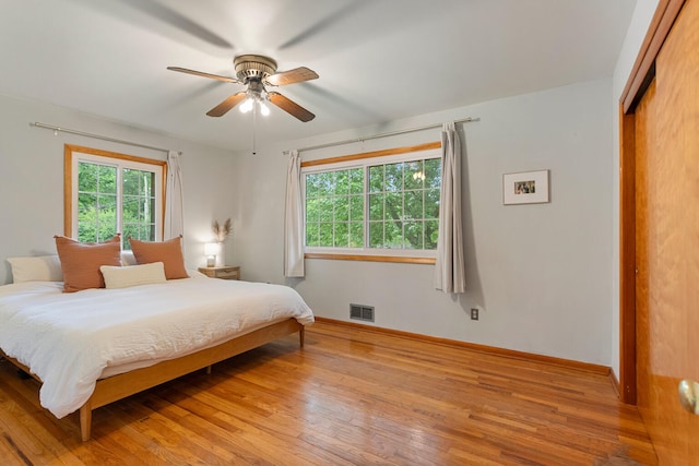 bedroom with multiple windows, ceiling fan, a closet, and light hardwood / wood-style floors