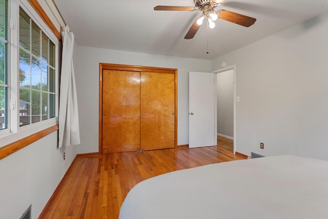 bedroom with light wood-type flooring, a closet, and ceiling fan