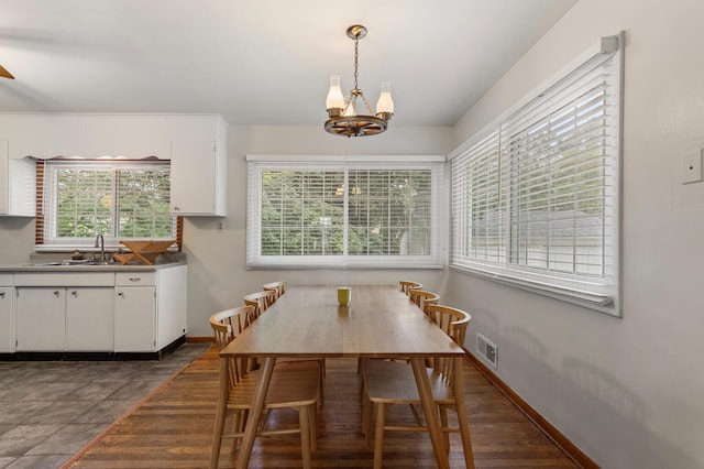 dining space with plenty of natural light, dark hardwood / wood-style flooring, sink, and an inviting chandelier