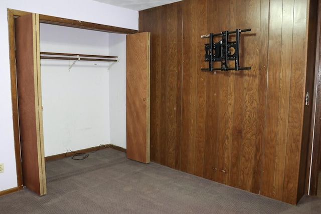 unfurnished bedroom featuring wood walls, a closet, and carpet floors