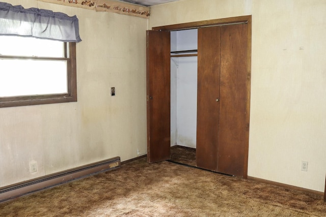 unfurnished bedroom with carpet, a closet, and a baseboard heating unit