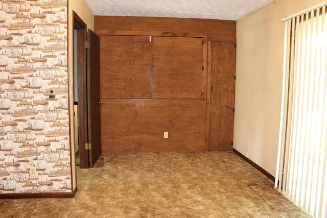 corridor featuring light carpet and a textured ceiling