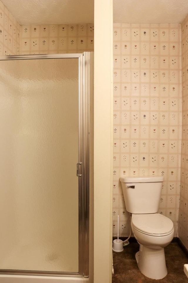 bathroom featuring a shower with door and toilet