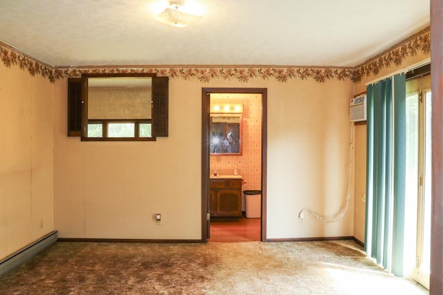 carpeted empty room featuring a wall mounted air conditioner, a textured ceiling, and baseboard heating