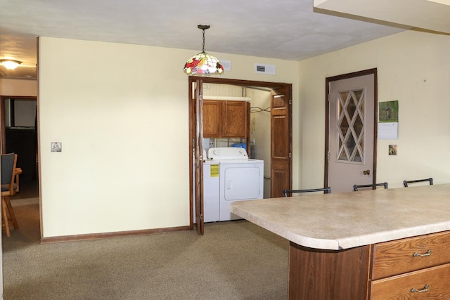 kitchen featuring pendant lighting, washer / dryer, kitchen peninsula, and carpet