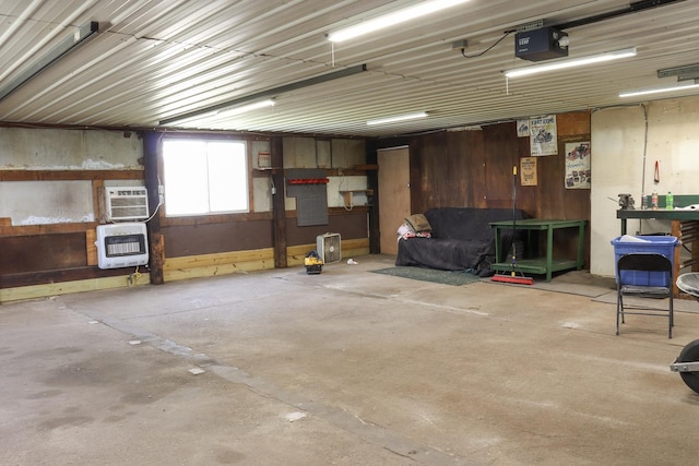 garage with heating unit, a garage door opener, and a wall mounted AC