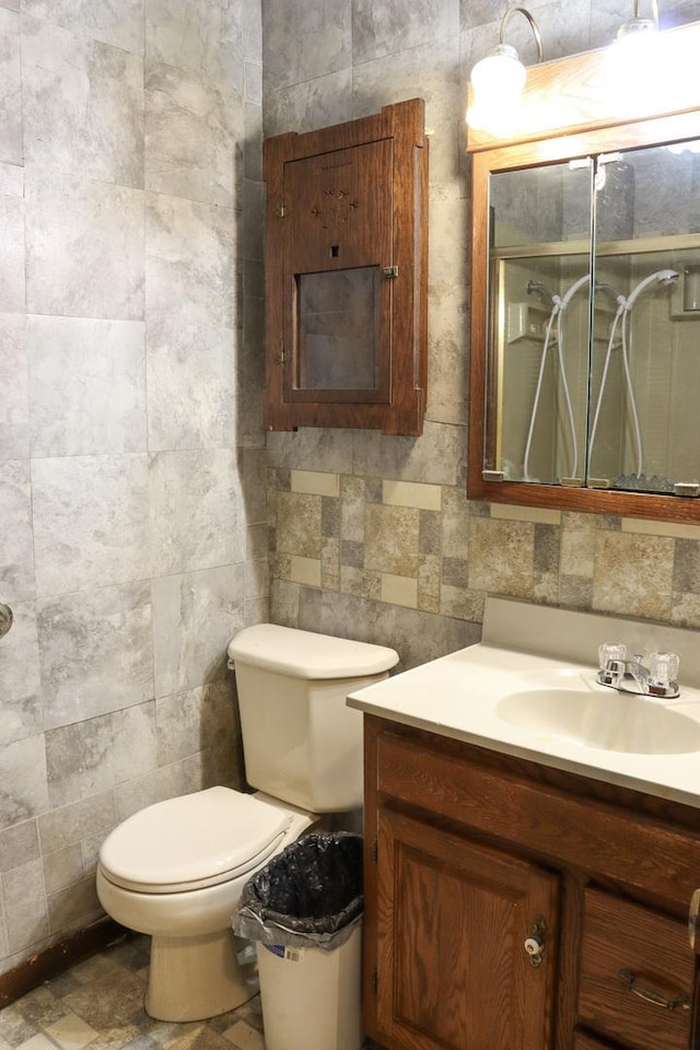 bathroom featuring vanity, toilet, and tile walls