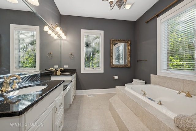 bathroom with a relaxing tiled tub, vanity, tile patterned flooring, and a wealth of natural light