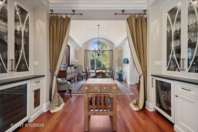 dining area with crown molding, beverage cooler, dark wood-type flooring, and a notable chandelier