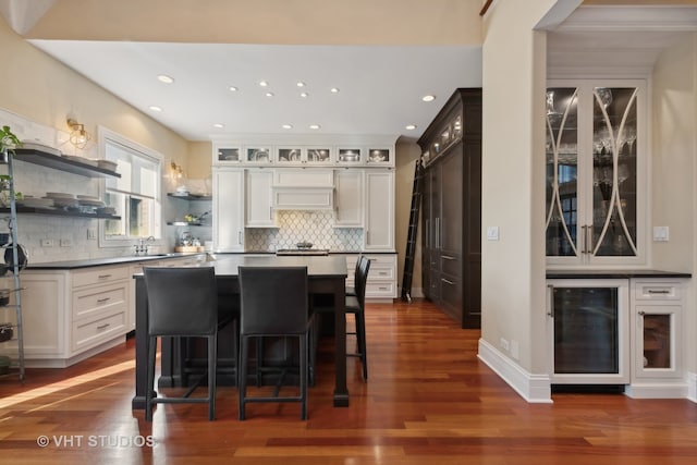 kitchen with decorative backsplash, a breakfast bar, white cabinets, dark hardwood / wood-style flooring, and ornamental molding