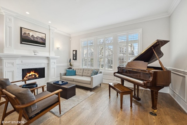 sitting room with hardwood / wood-style flooring, a premium fireplace, and crown molding