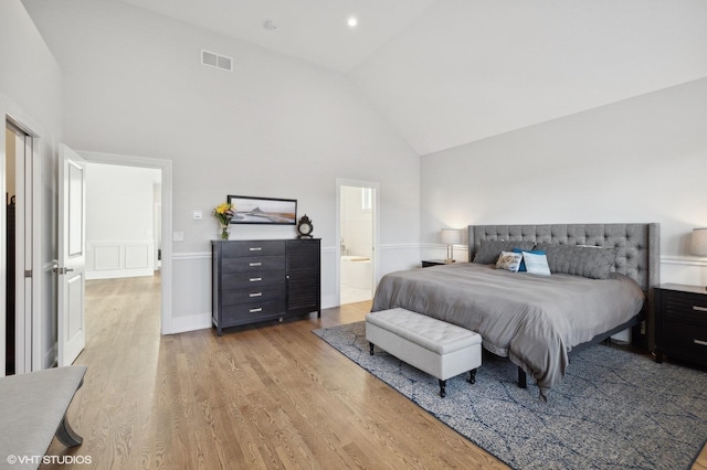 bedroom featuring connected bathroom, high vaulted ceiling, and hardwood / wood-style flooring