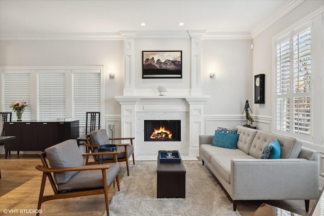 living room with light hardwood / wood-style flooring, ornamental molding, and a premium fireplace