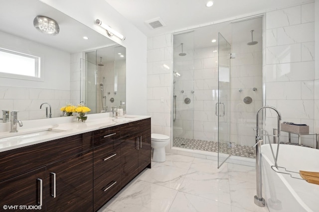 bathroom featuring vanity, a shower with door, toilet, and tile walls