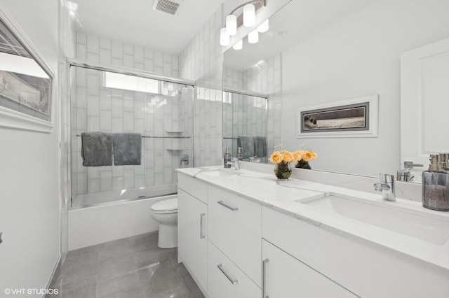 full bathroom featuring shower / bath combination with glass door, tile patterned floors, vanity, and toilet