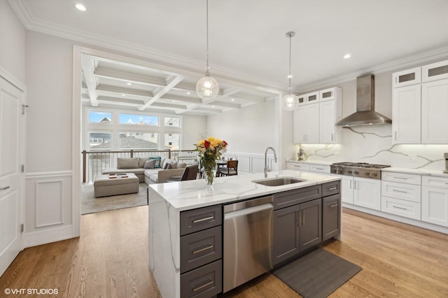 kitchen with coffered ceiling, stainless steel appliances, sink, wall chimney range hood, and beamed ceiling