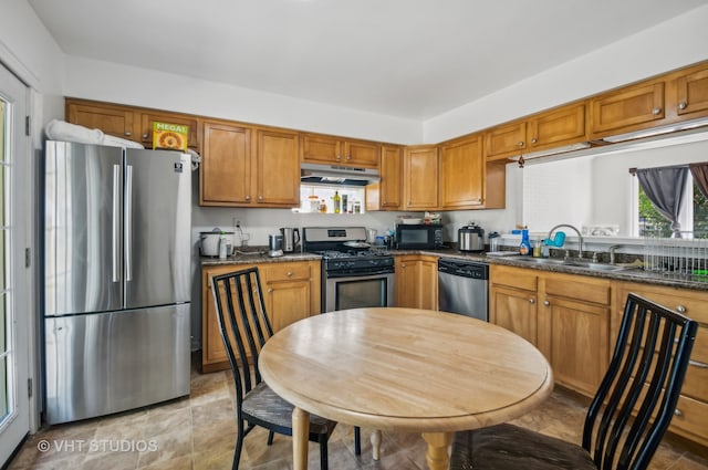 kitchen featuring stainless steel appliances, dark stone countertops, and sink